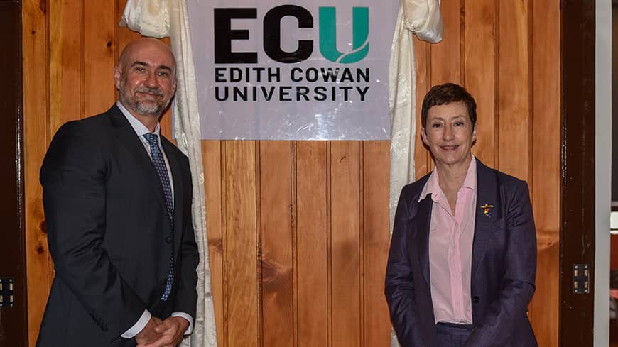 Two people standing in front of a logo