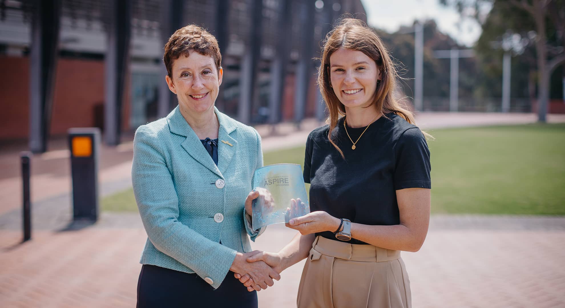Two women standing and holding an award